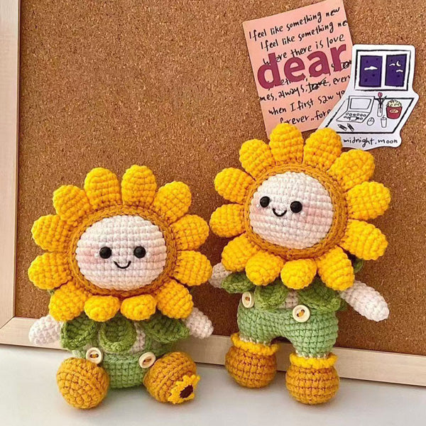 Crochet sunflower dolls standing upright in front of cork board