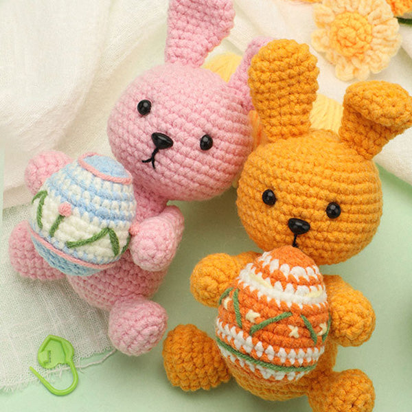 Handmade crochet Easter bunny amigurumi in pink and purple holding colored eggs, pair view | Knoblom