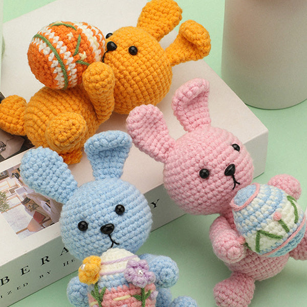 Handmade crochet Easter bunny finished doll in orange holding colored egg, close-up | Knoblom
