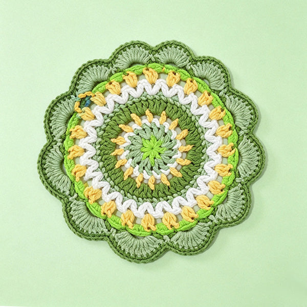 Handmade crochet green mandala coaster with a white cup placed on top