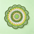 Handmade crochet green mandala coaster with a white cup placed on top