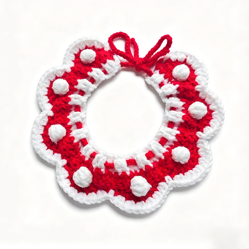 Handmade crochet pet collar in Christmas red with white pom-poms and red bow, flat lay \| Knoblom