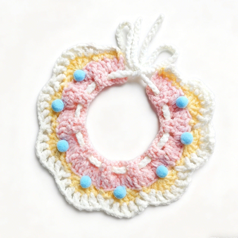 Handmade crochet pet collar in pink and yellow with blue pom-poms, flat lay \| Knoblom