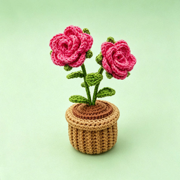 Handmade crochet rose flower pot decor on green background - two blooming pink roses