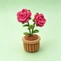 Handmade crochet rose flower pot decor on green background - two blooming pink roses