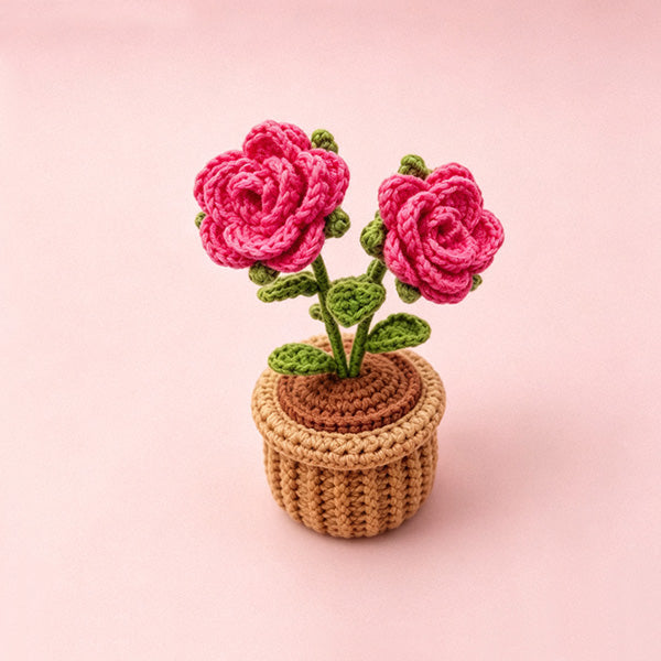 Handmade crochet rose flower pot decor on pink background - front view