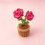 Handmade crochet rose flower pot decor on pink background - front view