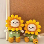 Two crochet sunflower dolls leaning against a wooden picture frame
