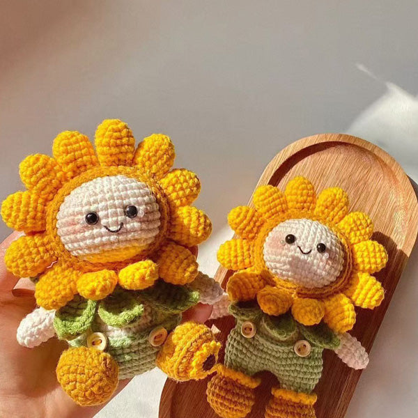 Two handmade crochet sunflower dolls held in hand, showing yarn texture and detail